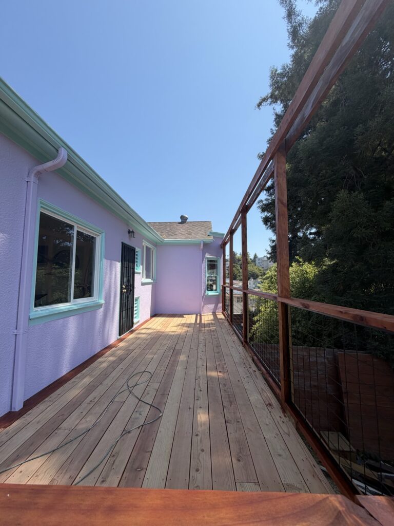 Weathered wood deck before staining, next to a lavender-painted house, by Wilmar's Painting