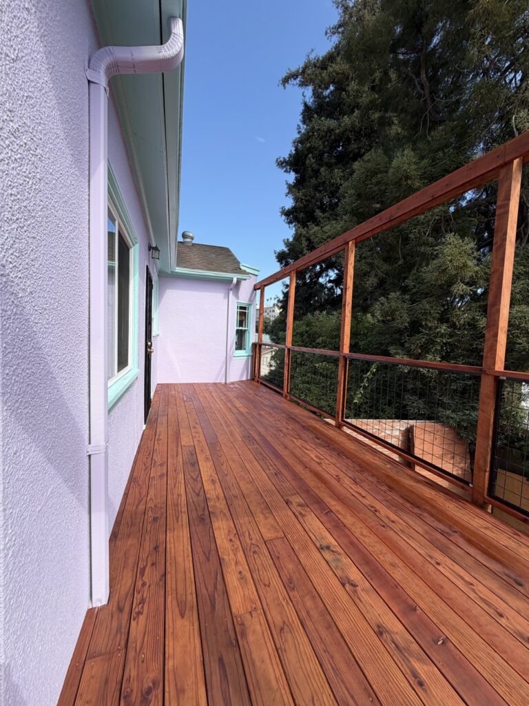 Close-up of a freshly stained wood deck with a glossy reddish-brown finish, by Wilmar's Painting