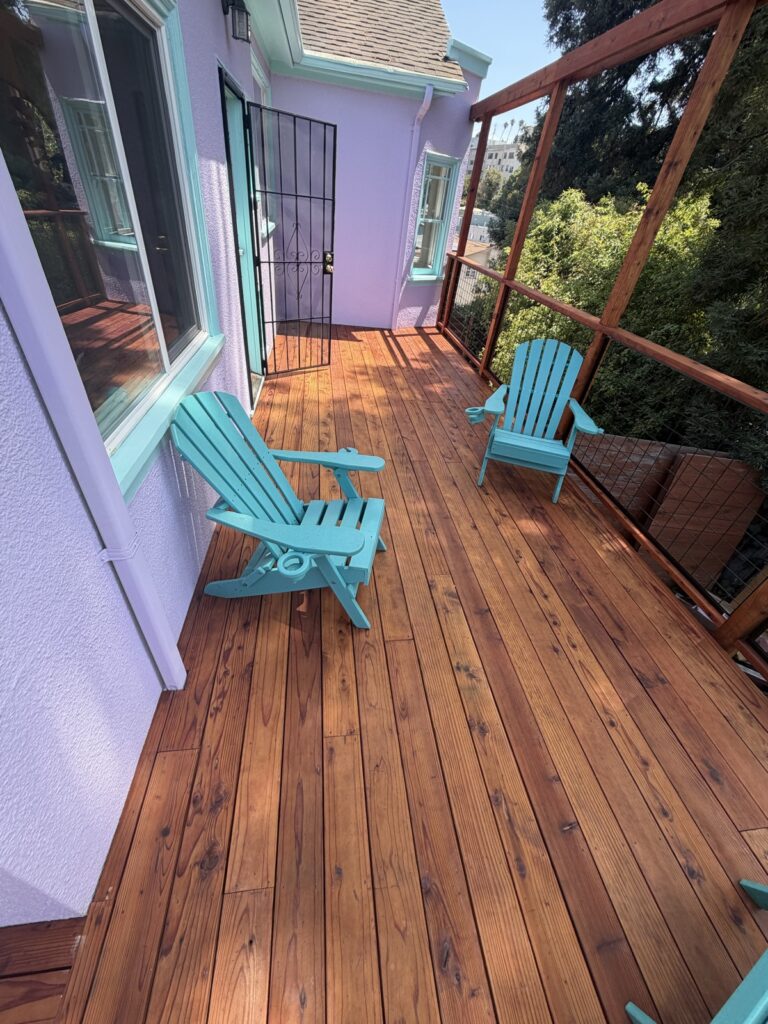 Finished deck staining with rich reddish-brown wood tone and teal patio chairs, by Wilmar's Painting
